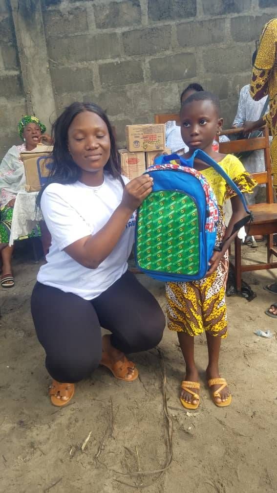 Une bénévole montre un sac d'école neuf à un garçon