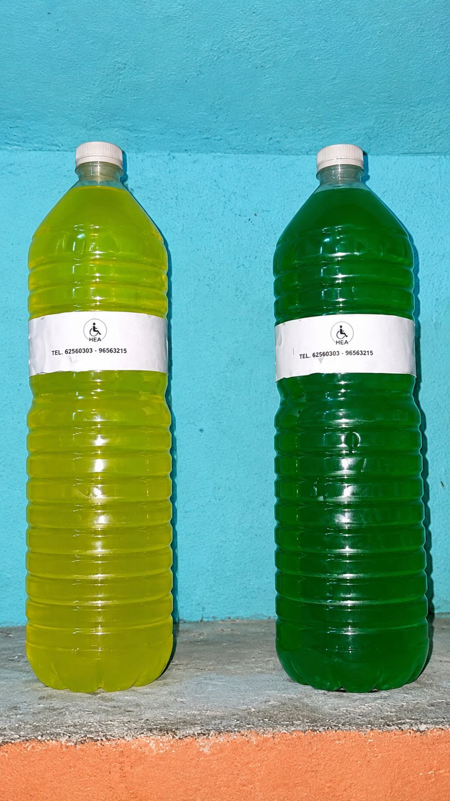 Deux bouteilles de savon liquide jaune et vert étiquetées HEA