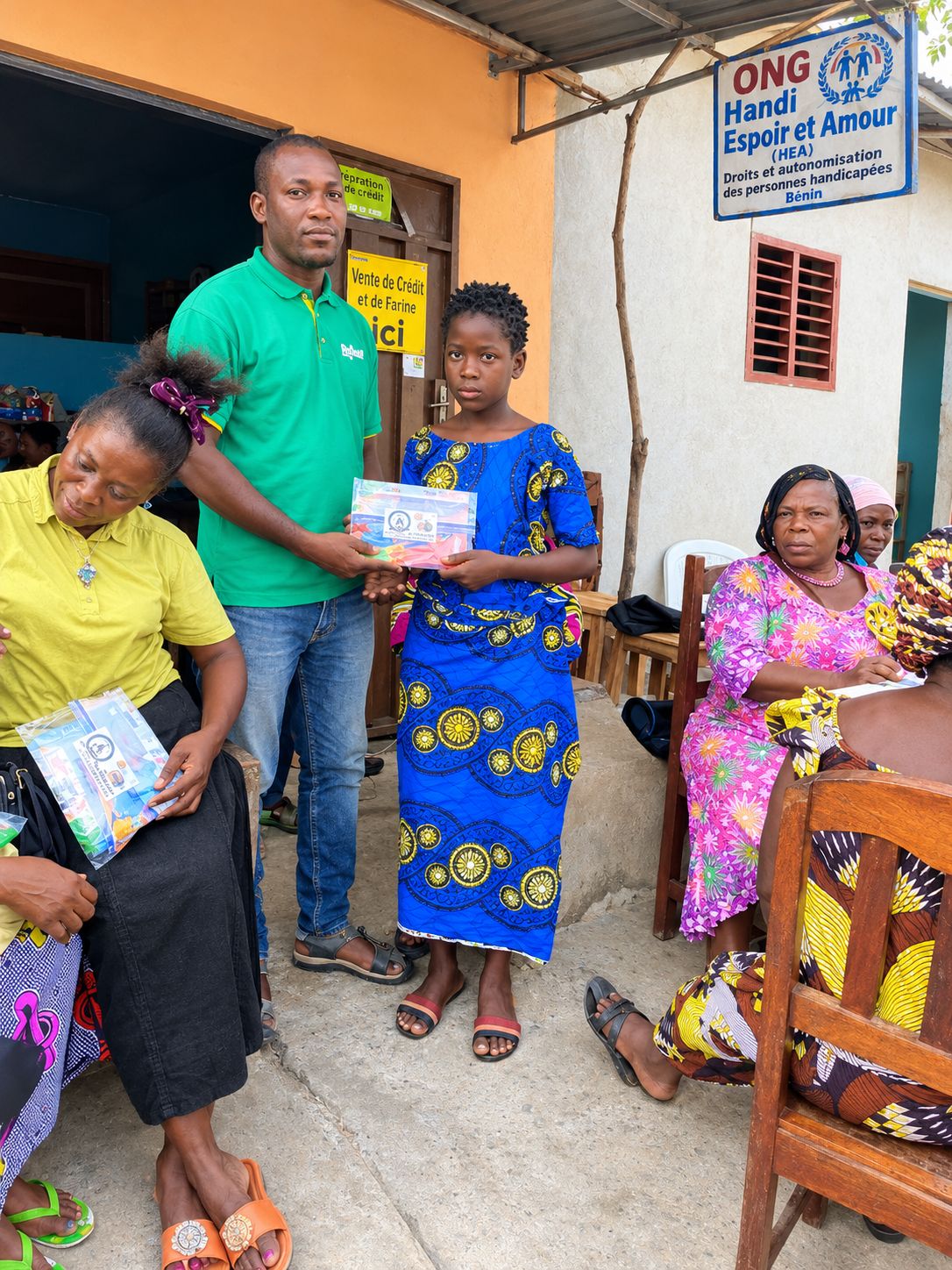 Une jeune fille reçoit ses fournitures devant l'ONG HEA